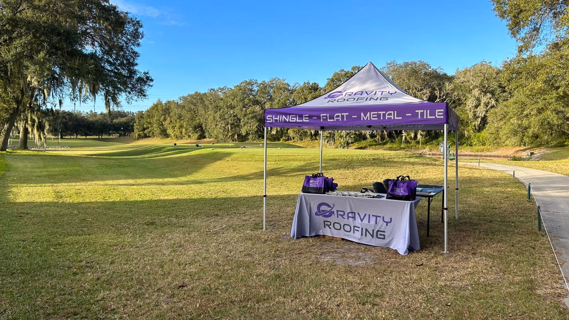 Gravity Roofing event tent set up on green grass at Arlington Ridge Golf Club for the Imagine South Lake Charter Golf Charity Event