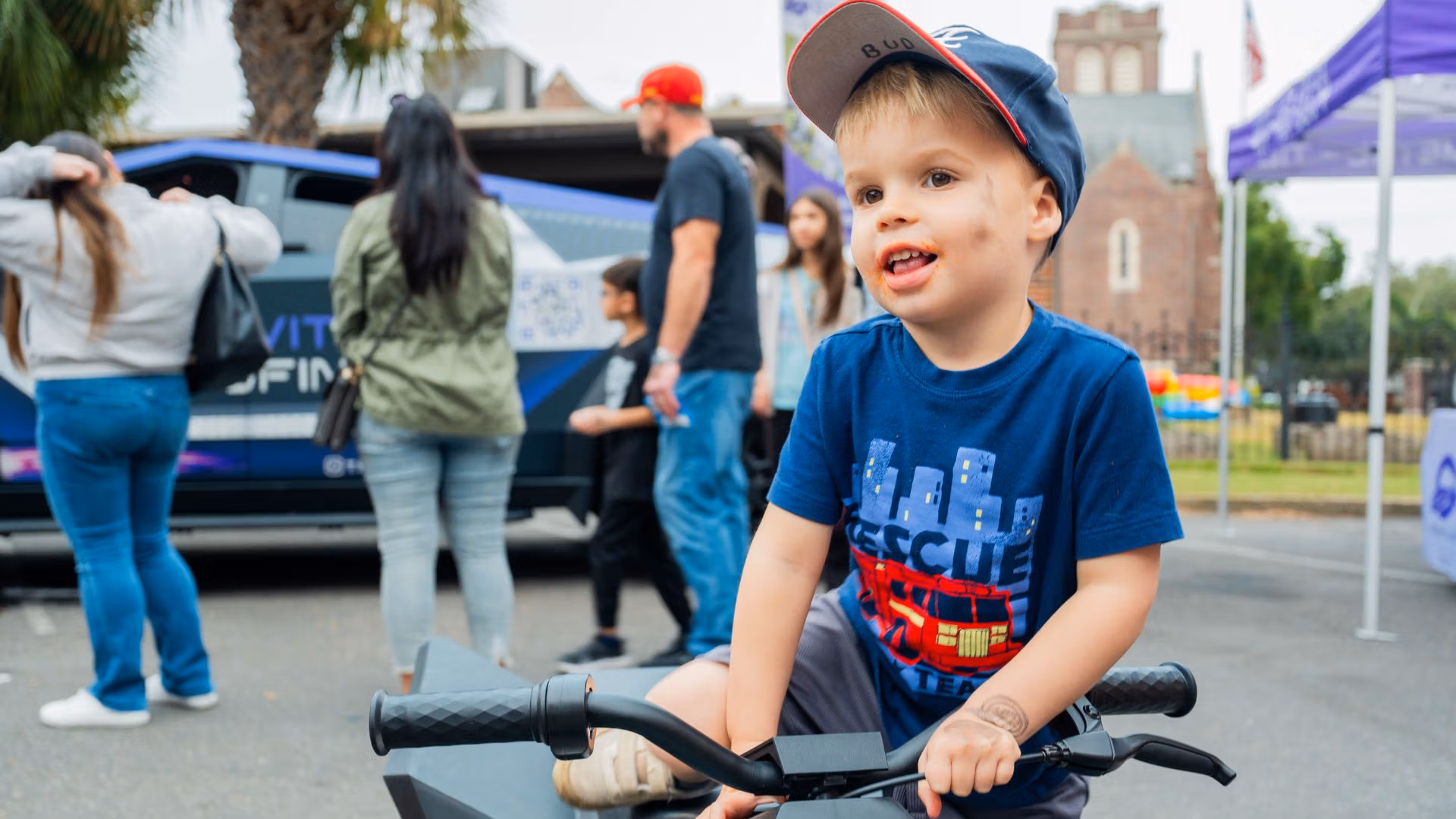 A young boy enjoying Touch-A-Truck 2025 in Orlando, Florida with Gravity Roofing’s Gravitron vehicle in the background at Trinity Downtown