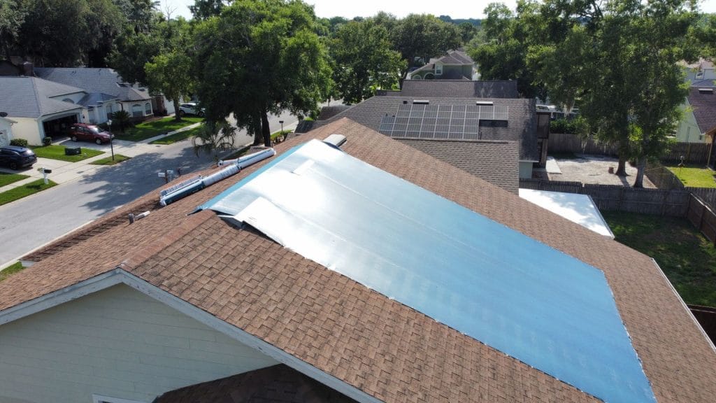 Emergency roofing tarp protecting a storm-damaged roof in Central Florida neighborhood
