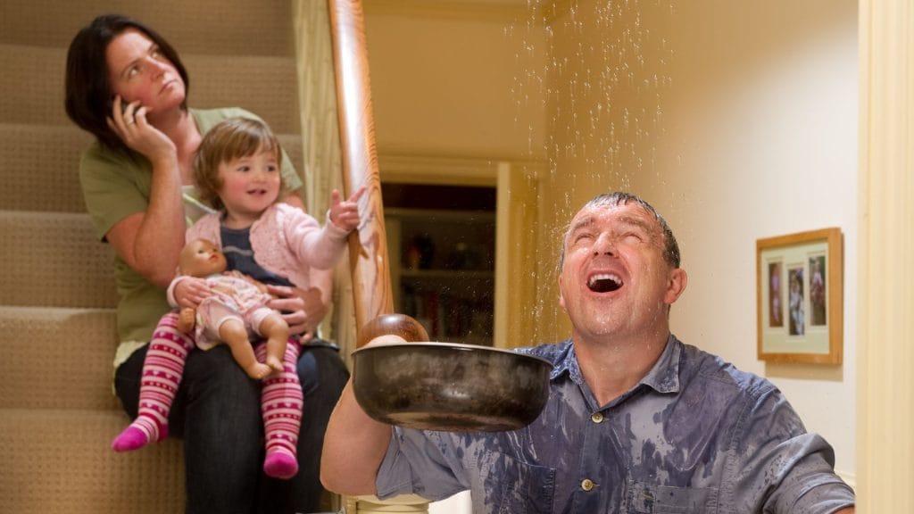 Man catching water from a roof leak in a bowl during emergency roofing situation in Central Florida.