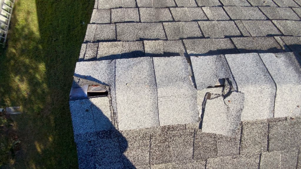 Cracked asphalt shingles on a roof in need of roof repair